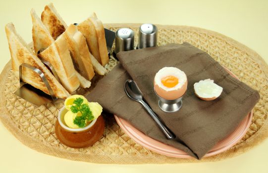 Freshly cracked boiled egg with toast and butter for breakfast.