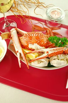 Cracked sand crab with lemon and white wine in a table setting.