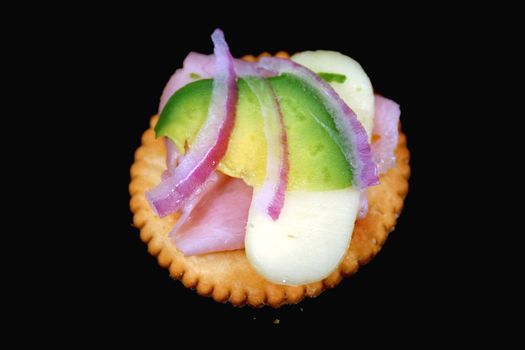 Yummy ham, avocado, cheese and onion cracker snack.