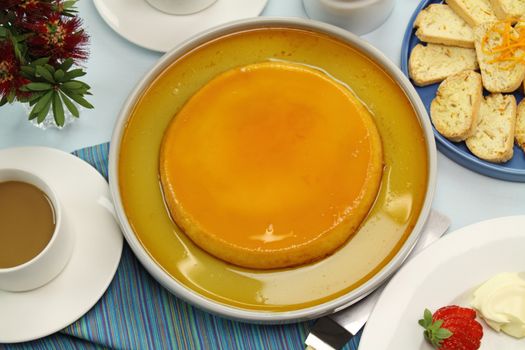 Creme caramel ready to be served with coffee and strawberries.