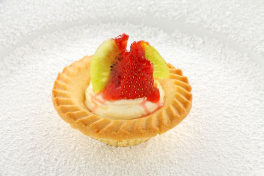 Delicious single cream and strawberry tar with kiwi fruit on a bed of icing sugar.