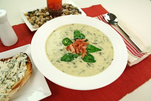 Creamy spinach soup with crispy bacon and spinach leaves.