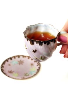 Antique cup of tea held by a female hand.