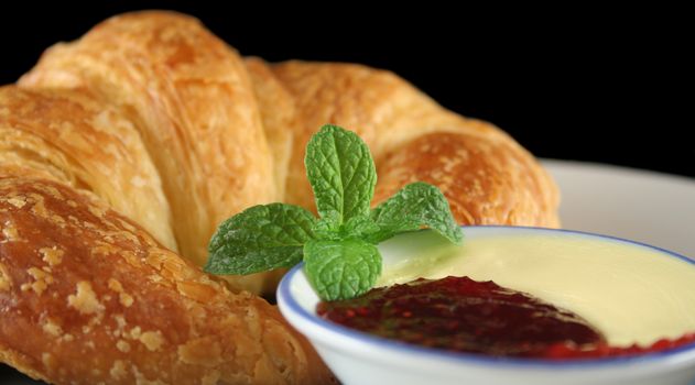 Mint garnish on jam and butter with a crisp croissant.