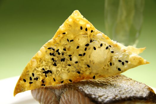 Crispy fried wonton wrapper with sesame seeds on a piece of salmon.