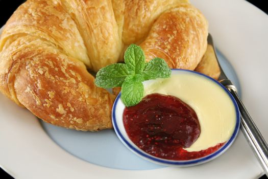 Delicious crisp and fresh croissant with strawberry jam and butter.
