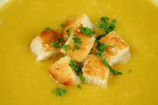 Croutons and parsley in piping hot pumpkin soup.