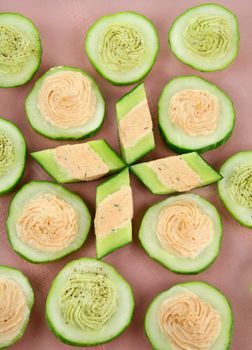 Delicious cucumber rounds with avocado and salmon with cream cheese.