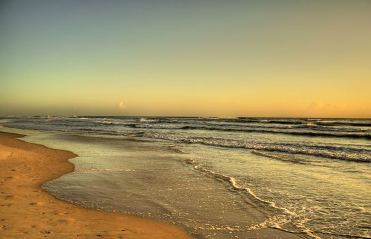 Waves roll in at dawn in the early morning golden light.