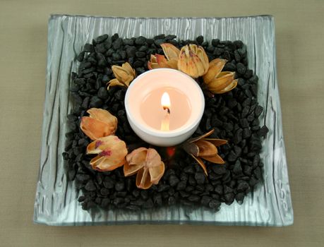 Tea candle set on stones with native seed pods.
