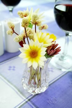 An arrangement of daisies in a vase on the dinner table.