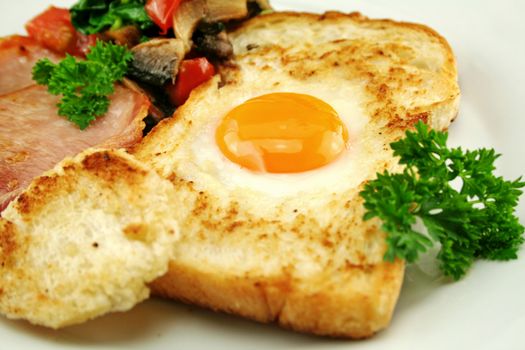 Egg embedded in toast with bacon, mushrooms, spinach and tomatoes.