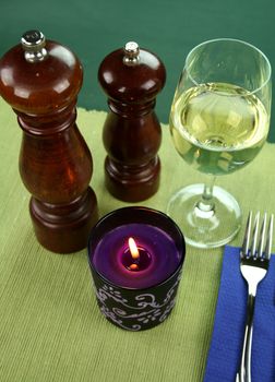 Mood lighting with a candle, salt and pepper mills and a glass of white wine.