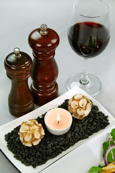 Salt and pepper grinders with a glass of red wine and a tea candle with decorations.