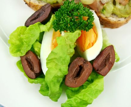 Side salad of boiled egg, lettuce and sliced olives.