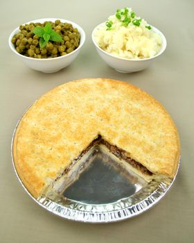 Family beef pie with peas and mashed potato ready to serve.