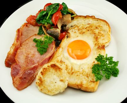 Egg embedded in toast with bacon, mushrooms, spinach and tomatoes.