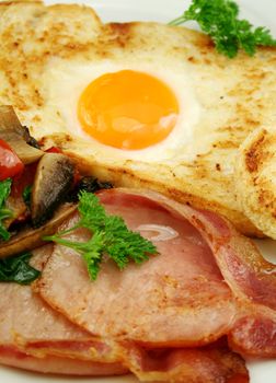 Egg embedded in toast with bacon, mushrooms, spinach and tomatoes.