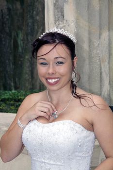 A lovely young bride outdoors wearing her wedding gown and tiara.