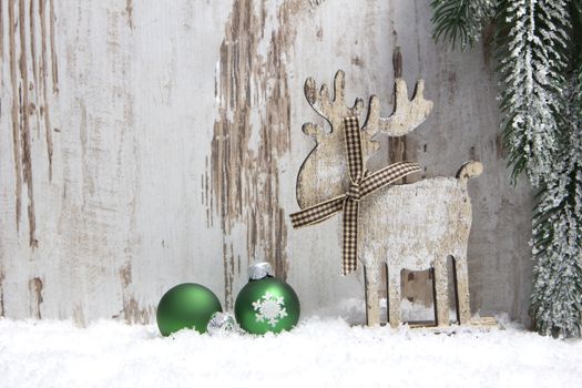 christmas decoration with wood background, snow, elk, christmas baubles green and fir branch 