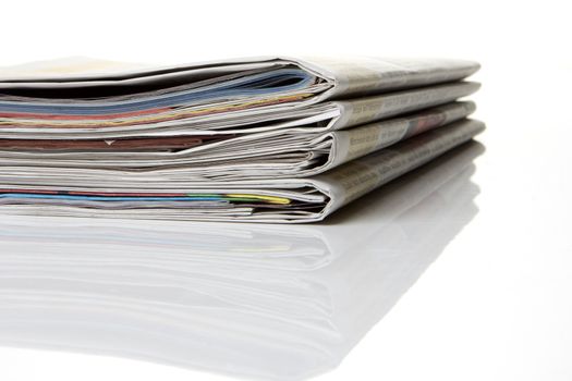 several newspapers, journals stacked on white background
