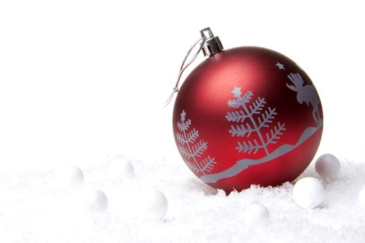 red christmas bauble with christmas tree on snow
