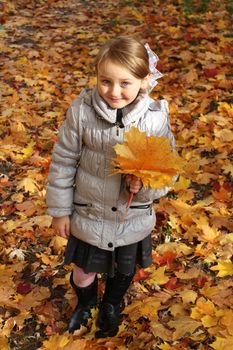 little girl with yellow leaf in the park in autumn