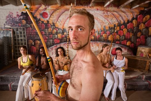 Serious male capoeira performer with group playing music