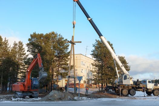 Installing a power pole on the outskirts of the settlements with the use of a truck crane and excavator