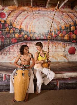 Cute mixed couple in capoeira clothing playing African music