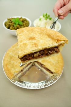 Slice of beef pie with peas and mashed potato ready to serve.
