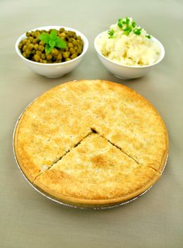 Family beef pie with peas and mashed potato ready to serve.