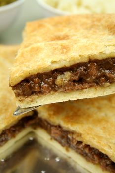 Slice of beef pie with peas and mashed potato ready to serve.