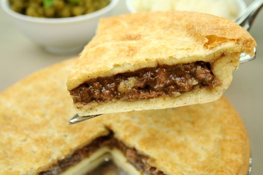 Slice of beef pie with peas and mashed potato ready to serve.