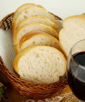 Sliced bread stick in a basket with red wine.