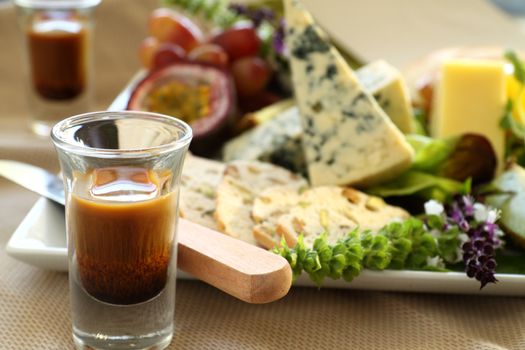 Delicious fruit and cheese platter featuring different cheeses and fresh fruits with a coffee liquer.