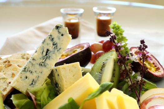 Delicious fruit and cheese platter featuring different cheeses and fresh fruits with a coffee liquer.