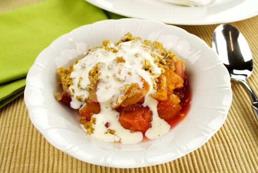 Seasonal fruit crumble dessert with cream ready to serve.