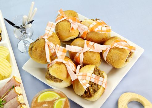 Tied up mini beef burgers served with other finger food.