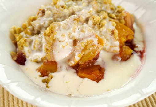 Seasonal fruit crumble dessert with cream ready to serve.