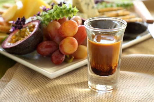 Delicious fruit and cheese platter featuring different cheeses and fresh fruits with a coffee liquer.