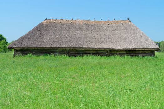 Typical ancient big village shed with straw roof in Ukrainian countryside 