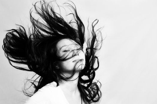 Portrait of beautiful young woman flicking her hair and posing, black and white style