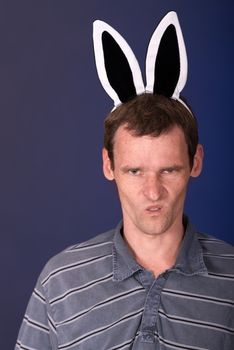 Very angry man with rabbit ears on dark background