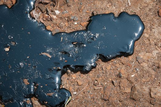 Black oily liquid pitch against the brown earth fuse under heat sun