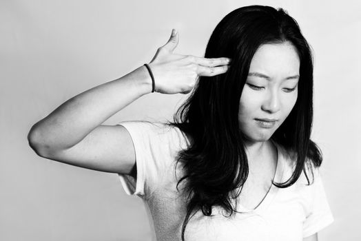 Portrait of depressed young woman hand signals suicide, black and white style