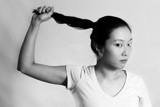 Portrait of lonely young woman pulling her hair looking frustrated, black and white style