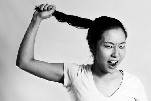 Portrait of lonely young woman pulling her hair looking frustrated, black and white style