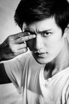 Portrait of handsome young man covering one eye with two fingers, black and white style