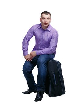 Man going on a trip and sits on a suitcase, isolated on white background